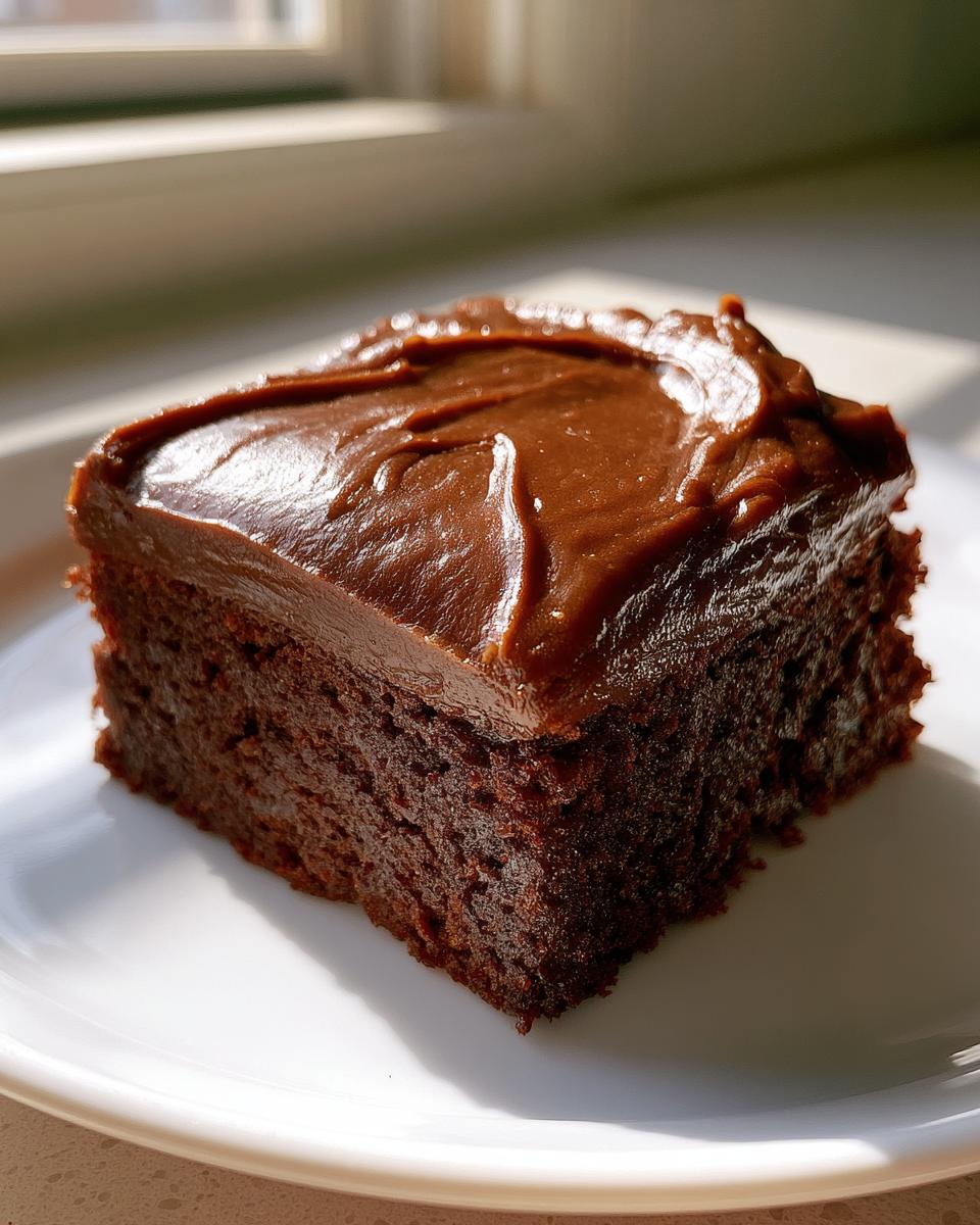 Lunch Lady Brownies: 1-Pan Fudgy Nostalgia 5 A close-up of a fudgy Lunch Lady Brownie slice with rich chocolate frosting on a white plate.